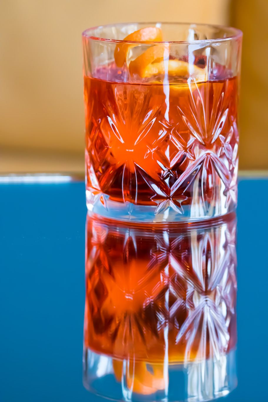 Negroni in a cut crystal glass reflected on a blue surface