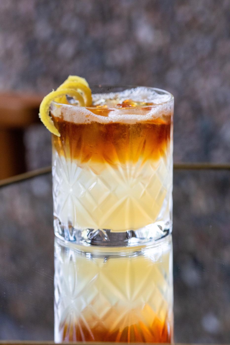 Layered Pimm's sour with a lemon twist
