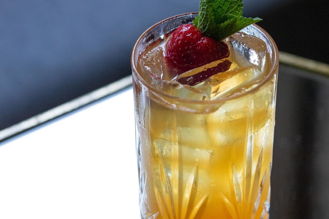 Whiskey Pimm's Cup in a tall crystal glass with a strawberry and mint garnish