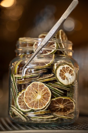Jar of dehydrated citrus wheels with garnish tweezers