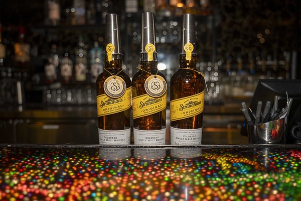 Three whiskey bottles on a bar top